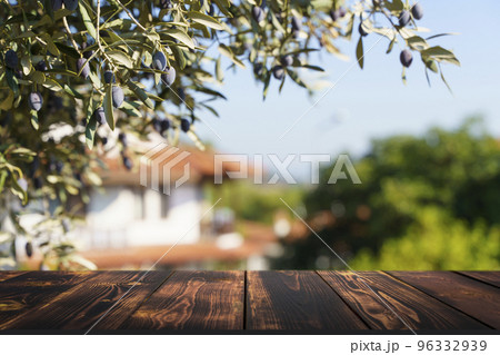 Wooden table on the background of olive trees and a farm garden. Summer rustic food product background. Eco, natural, farming concept Wooden table on the background of olive trees and a farm garden. Summer rustic food product background. Eco, natural, farming concept 96332939