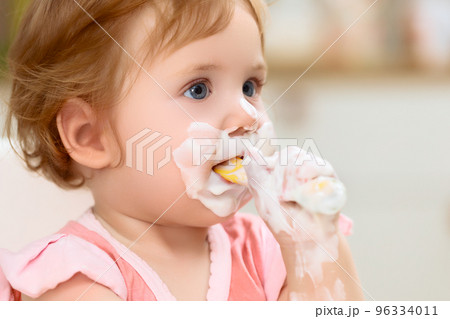 A mother feeds a cheerful baby with cottage cheese A mother feeds a cheerful baby with cottage cheese 96334011