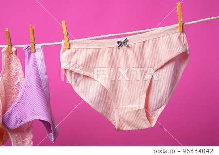 Female panties hanging on rope against pink studio background Female panties hanging on rope against pink studio background 96334042