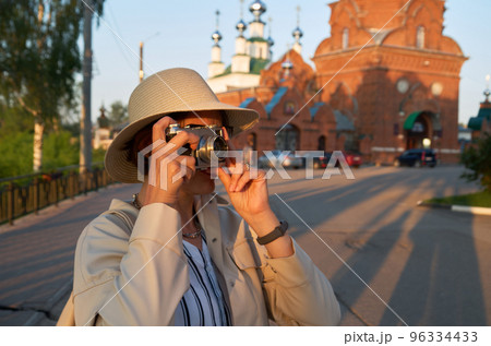 Woman tourist in a straw hat takes pictures on the street with a vintage camera 96334433