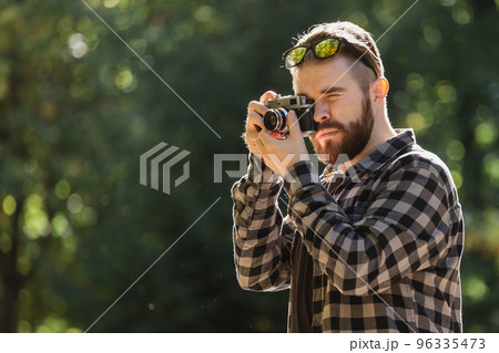 Portrait man photographer taking picture with vintage camera on city green park copy space and place for text - leisure activity and hobby concept Portrait man photographer taking picture with vintage camera on city green park copy space and place for text - leisure activity and hobby concept 96335473
