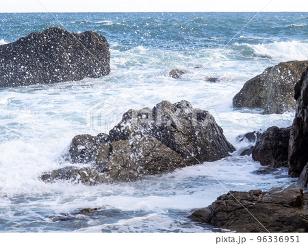 海岸の岩場に荒波が打ち寄せて波しぶきが飛ぶ。 96336951