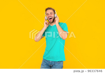 cheerful man in blue shirt wear earphones on yellow background, lifestyle 96337646