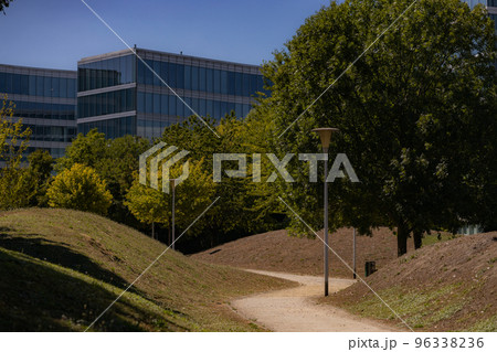 Beautiful s-shape path in park with trees and buildings 96338236