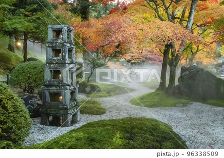 霧の漂うモミジと石灯籠のある日本庭園 96338509