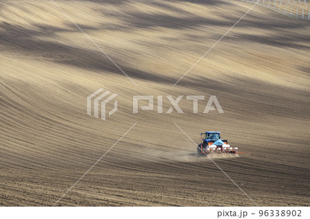 Tractor with seed drill in early spring landscape 96338902