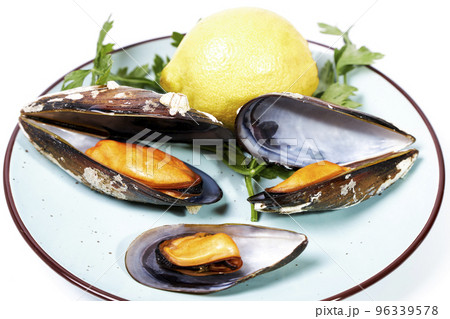 Dish with steamed mussels with parsley and lemon on a white background Dish with steamed mussels with parsley and lemon on a white background 96339578