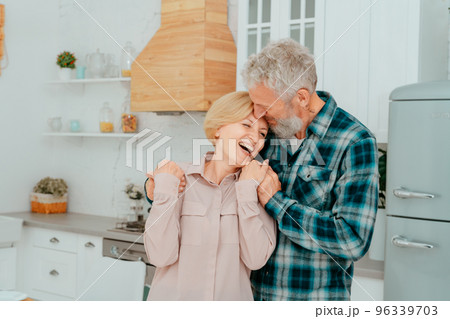 Retired husband and wife hug each other at home 96339703