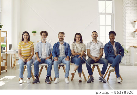 Portrait of smiling multiracial young people in casual clothes sitting in row on chairs. Portrait of smiling multiracial young people in casual clothes sitting in row on chairs. 96339926