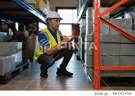 Working at warehouse. Male warehouse worker checking in storage department. Employee organizing goods distribution to the market. 96341456