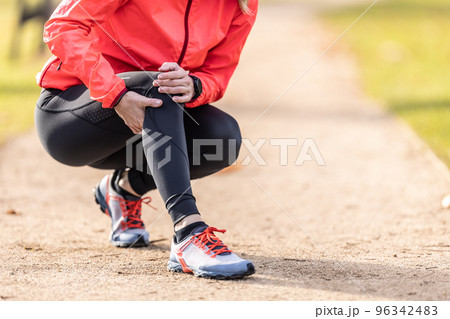 A young athlete sprained her knee while running, she holds it in pain 96342483