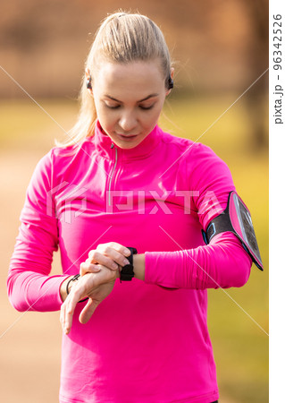 A young sportswoman turns on her smartwatch before running 96342526
