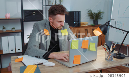 Tired sad exhausted businessman working on laptop at office with many sticker tasks, panic attack 96343905