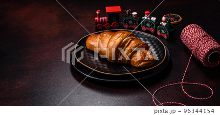 Beautiful different Christmas decorations and croissant on a brown concrete table Beautiful different Christmas decorations and croissant on a brown concrete table 96344154