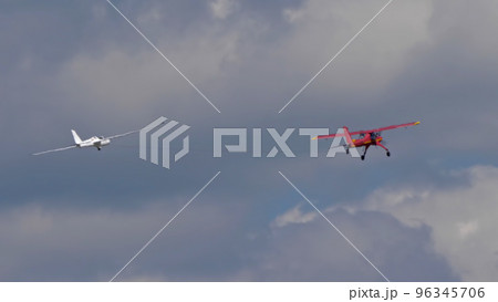 Red small sport plane flying in the sky pulls on a rope the glider plane 96345706