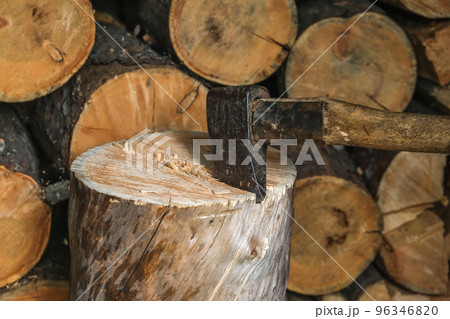 A man is chopping logs with an axe on chopping 96346820