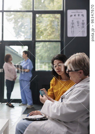 Senior medic measuring insulin level and glucose in blood sample using glucometer instrument, consulting asian patient with diabetes. Doctor doing medical test with diabetic woman, medicine support 96347670