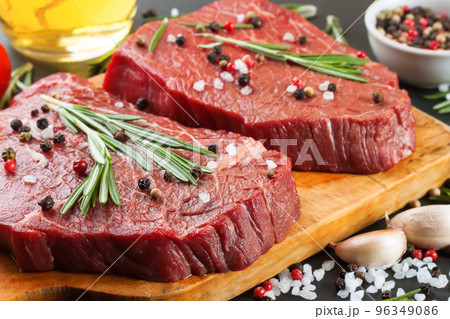 Fresh raw beef steak with spice on black slate background Fresh raw beef steak with spice on black slate background 96349086