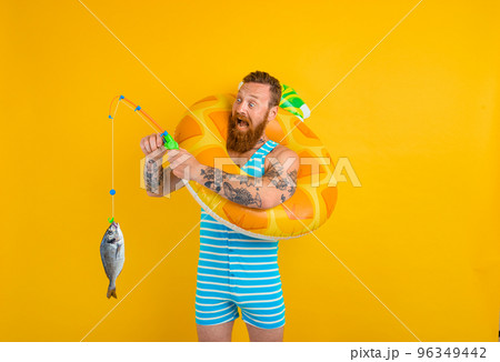 Man with beard and inflatable donut catches fish Man with beard and inflatable donut catches fish 96349442
