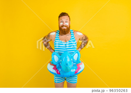 Thoughtful man with inflatable donut with elephant is ready to swim 96350263