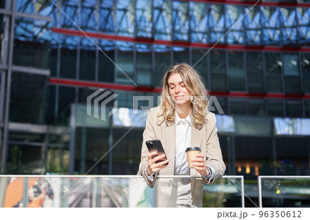 Corporate woman drinking her coffee and looking at mobile phone. Businesswoman relaxing on her lunch break Corporate woman drinking her coffee and looking at mobile phone. Businesswoman relaxing on her lunch break 96350612
