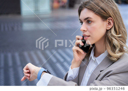 Busy lady manager talking on mobile phone on street, going on a meeting, checking time on watch 96351246