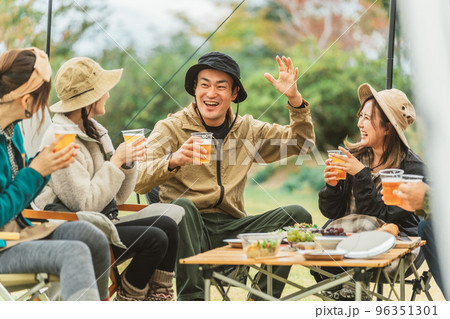 秋冬のキャンプ場で仲間と一緒にビールを飲みながら冗談を言って盛り上げる人気者のアジア人男性 96351301