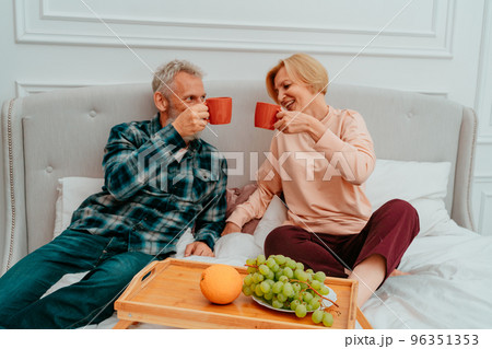 husband and wife have breakfast on the bed with coffee and fruit 96351353