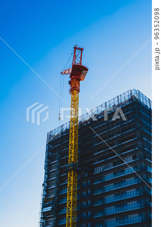 建設中の高層マンション そびえるクレーンと快晴の空 タテ 高彩度コントラスト 建設中の高層マンション そびえるクレーンと快晴の空 タテ 高彩度コントラスト 96352098
