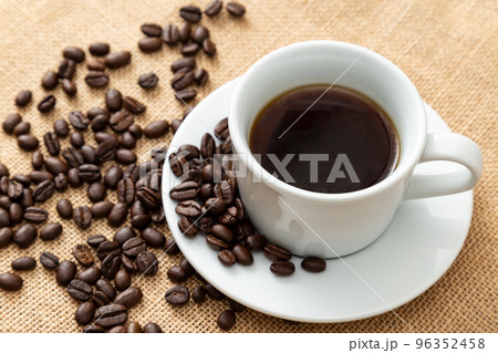 麻袋の上にこぼれたコーヒー豆とコーヒーカップ 96352458