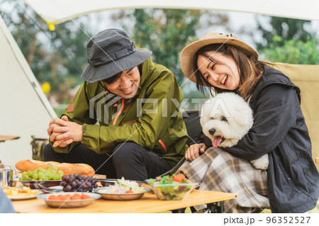 秋冬のキャンプ場で犬と一緒に料理を作るカップルキャンパー 96352527