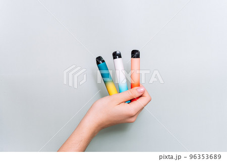 Electronic three cigarettes in female hand against green background Electronic three cigarettes in female hand against green background 96353689