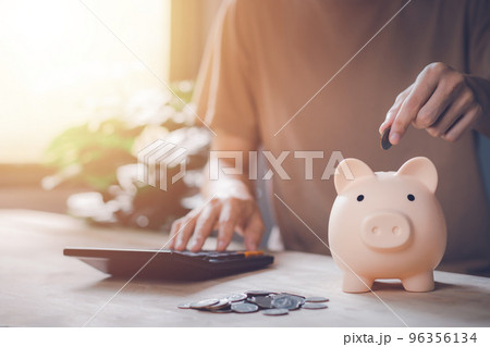 Man hand holding coin with piggy bank and calculator on wood table. Saving money wealth and financial concept. Business, finance, investment, Financial planning. Man hand holding coin with piggy bank and calculator on wood table. Saving money wealth and financial concept. Business, finance, investment, Financial planning. 96356134