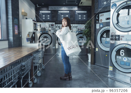 コインランドリーでランドリーバッグを持つ若い女性 コインランドリーでランドリーバッグを持つ若い女性 96357206