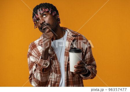 Young african man holding cup of take away coffee over yellow background Young african man holding cup of take away coffee over yellow background 96357477