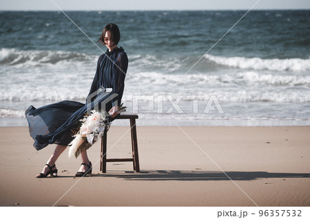 海辺で椅子にブーケを持って座る女性 96357532