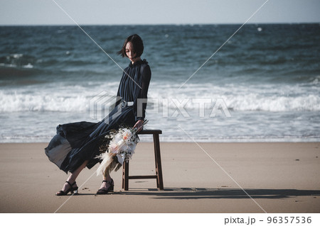 海辺で椅子にブーケを持って座る女性 96357536