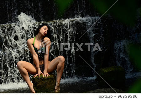 Young brunette model posing against a waterfall 96359586