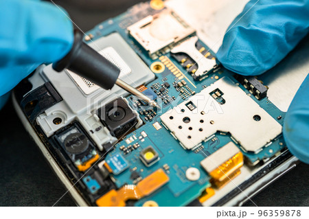 Technician repairing inside of mobile phone by soldering iron. Integrated Circuit. the concept of data, hardware, technology. 96359878