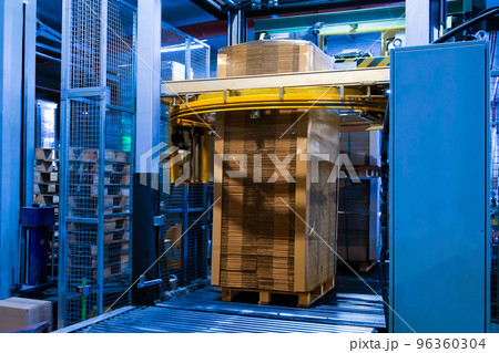 Industrial equipment - typical stretch wrapping machine in process of work. Packaging of corrugated cardboard. Selective focus. Industrial equipment - typical stretch wrapping machine in process of work. Packaging of corrugated cardboard. Selective focus. 96360304