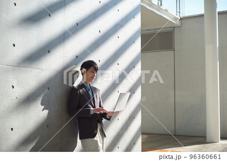 立ちながらパソコンを操作する男性 96360661