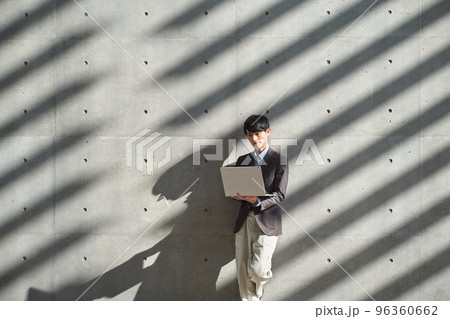 立ちながらパソコンを操作する男性 96360662