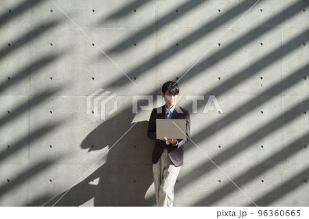 立ちながらパソコンを操作する男性 96360665