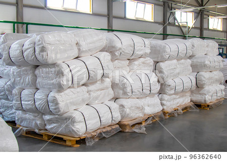 Large white bags with finished products are stacked on pallets and are in the warehouse. Large white bags with finished products are stacked on pallets and are in the warehouse. 96362640