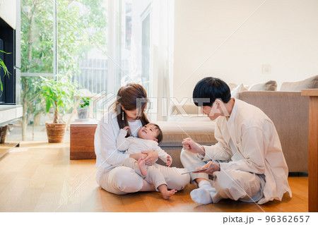 赤ちゃんに絵本の読み聞かせをする両親 96362657