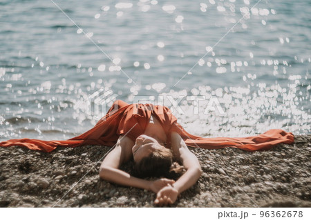 Woman in red dress on sea. Side view a Young beautiful sensual woman in a red long dress posing on the beach near sea on sunset. Girl on the nature on blue sky background. Fashion photo. Woman in red dress on sea. Side view a Young beautiful sensual woman in a red long dress posing on the beach near sea on sunset. Girl on the nature on blue sky background. Fashion photo. 96362678