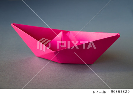 Pink paper boat origami isolated on a grey background Pink paper boat origami isolated on a grey background 96363329