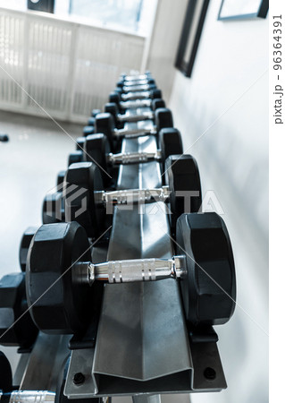 Rack with dumbbells of different weights close up 96364391