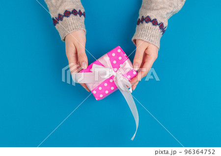 Small gift box in female hands on blue background, view from above Small gift box in female hands on blue background, view from above 96364752
