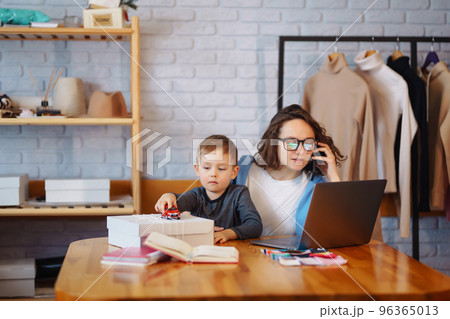Young mother works with little boy. Business Woman talking on the phone and discussing work issues. 96365013